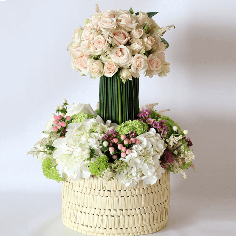pink and white flower arrangement Spray rose, astilbe on a steal grass podium on white hydrangea, hypericum and snowball in a basket