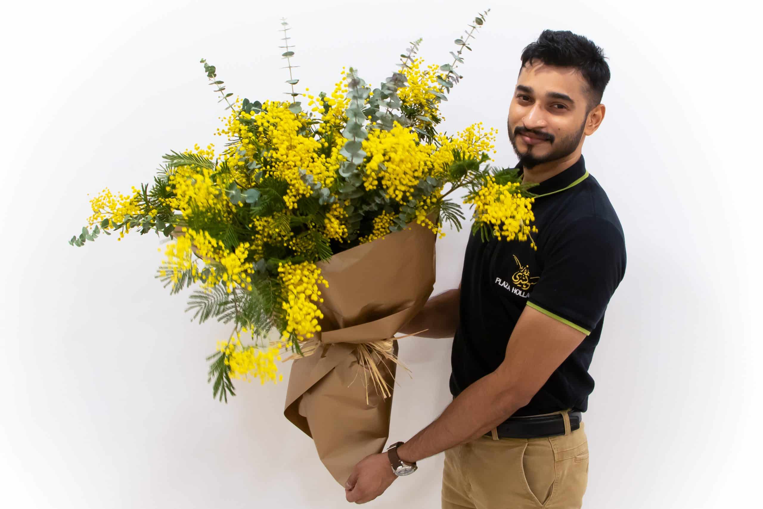 H Q Plaza Hollandi staff holding a mimosa flower bouquet