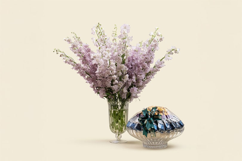 5 Elegant purple delphinium arrangement with chocolates in a clear glass vase. Height 60cm. Perfect luxury floral gift for celebrations and special occasions.